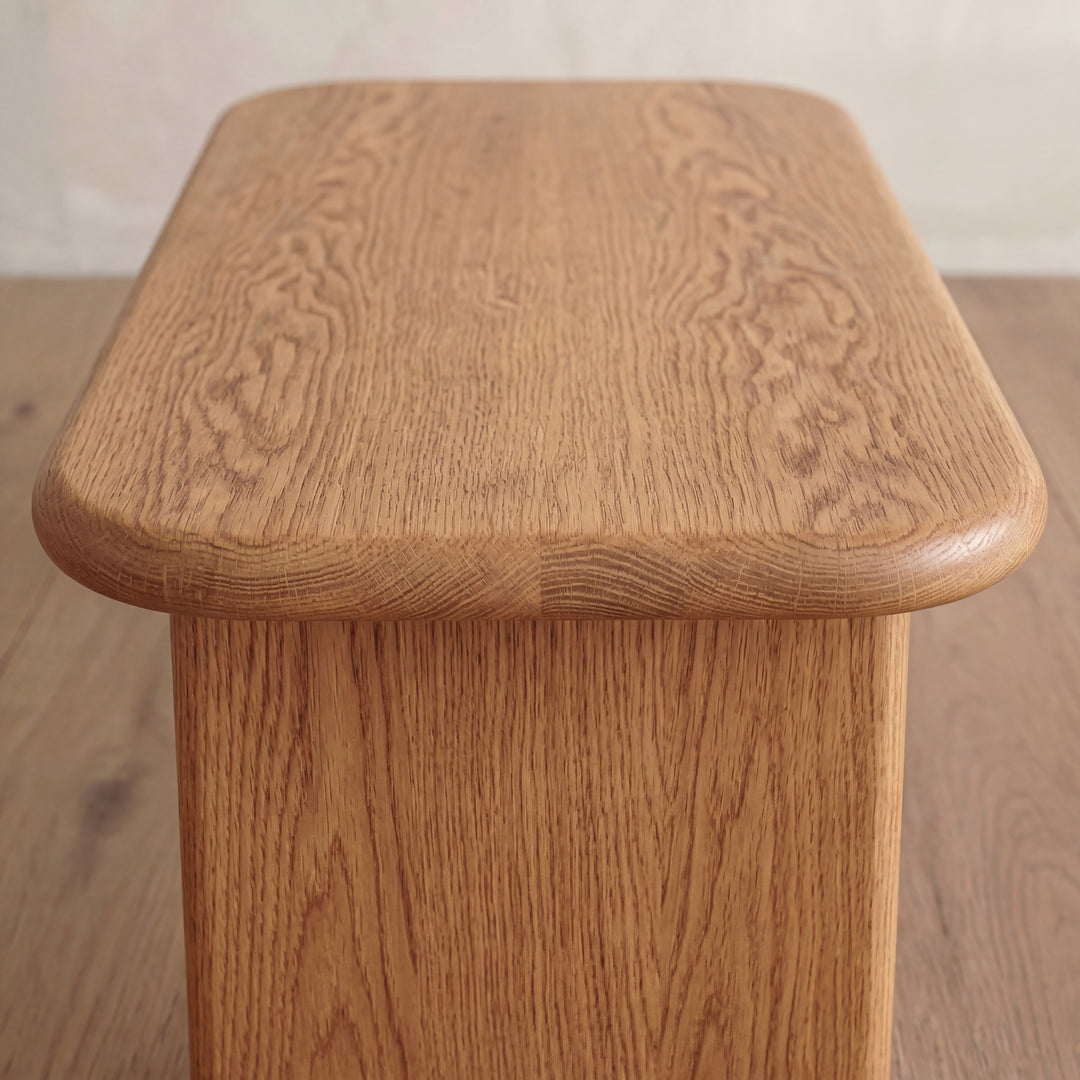 Close-up of a 60 inch coffee table in red oak, handmade with a rectangular top, rounded edges, and visible wood grain, shown on a wooden floor.