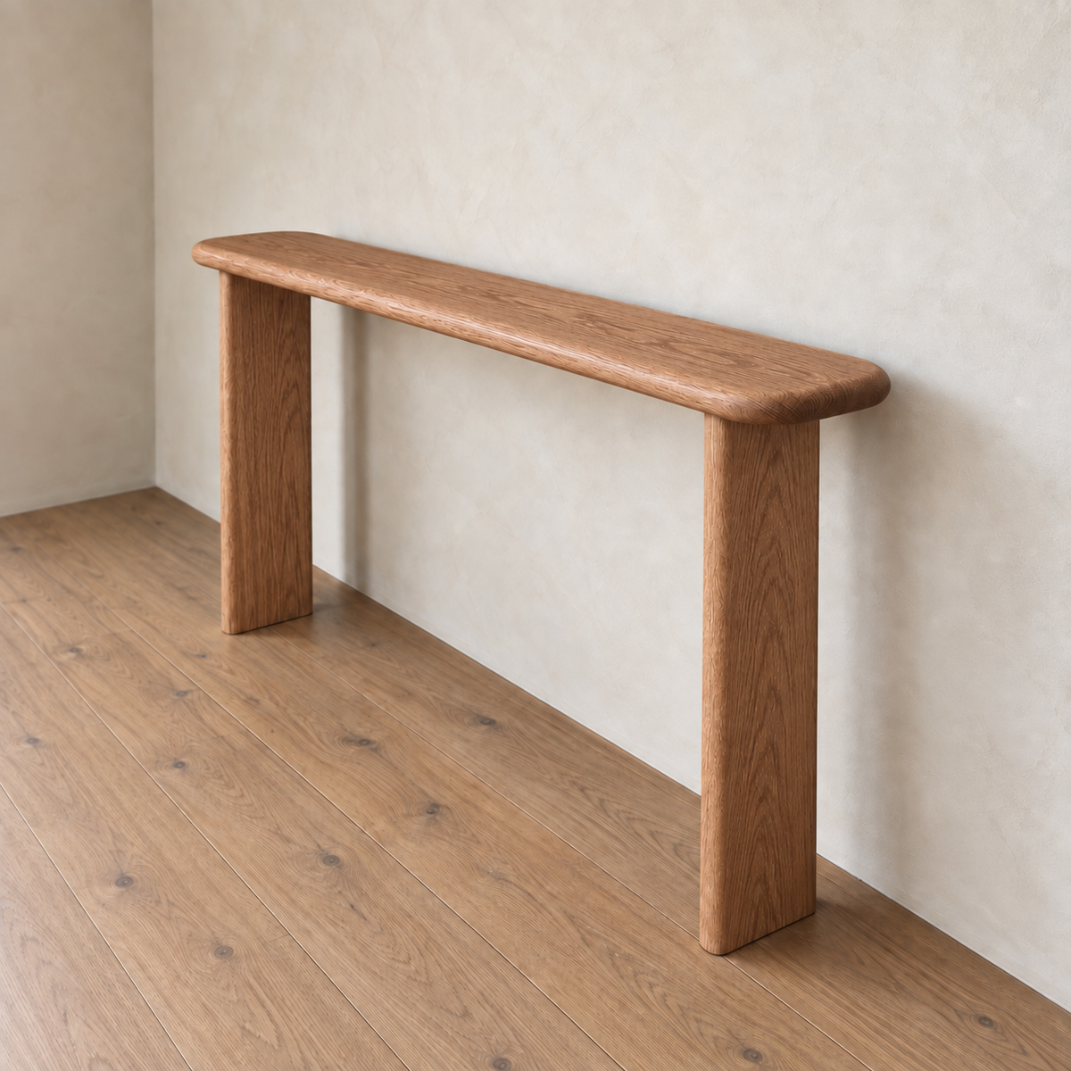 The Narrow console table in red oak, handmade in Vancouver with rounded edges, stands against a beige wall on a wooden floor.
