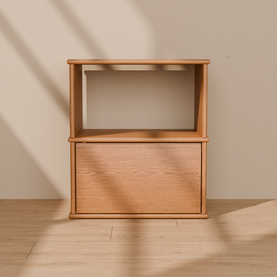 Front view of the solid wood nightstand in red oak, showing the open shelf, the drawer and the rounded edges of the top, shelf and base.