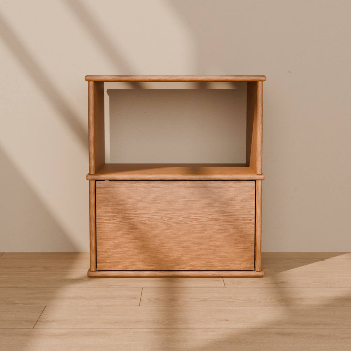 Front view of the solid wood nightstand in red oak, showing the open shelf, the drawer and the rounded edges of the top, shelf and base.