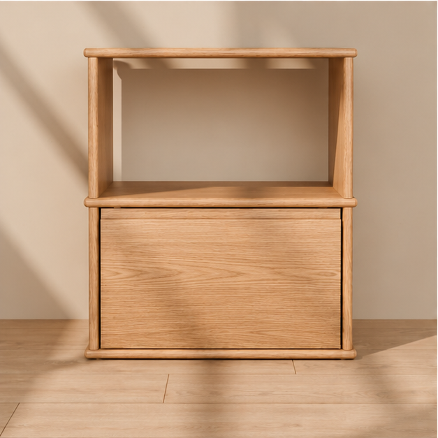 Front view of the solid wood nightstand in white oak, showing the open shelf, the drawer and the rounded edges of the top, shelf and base.