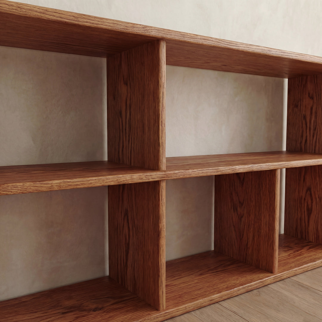 A close-up of the 65 inch bookshelf TV stand in red oak, featuring six rectangular compartments, displayed against a light-colored wall.