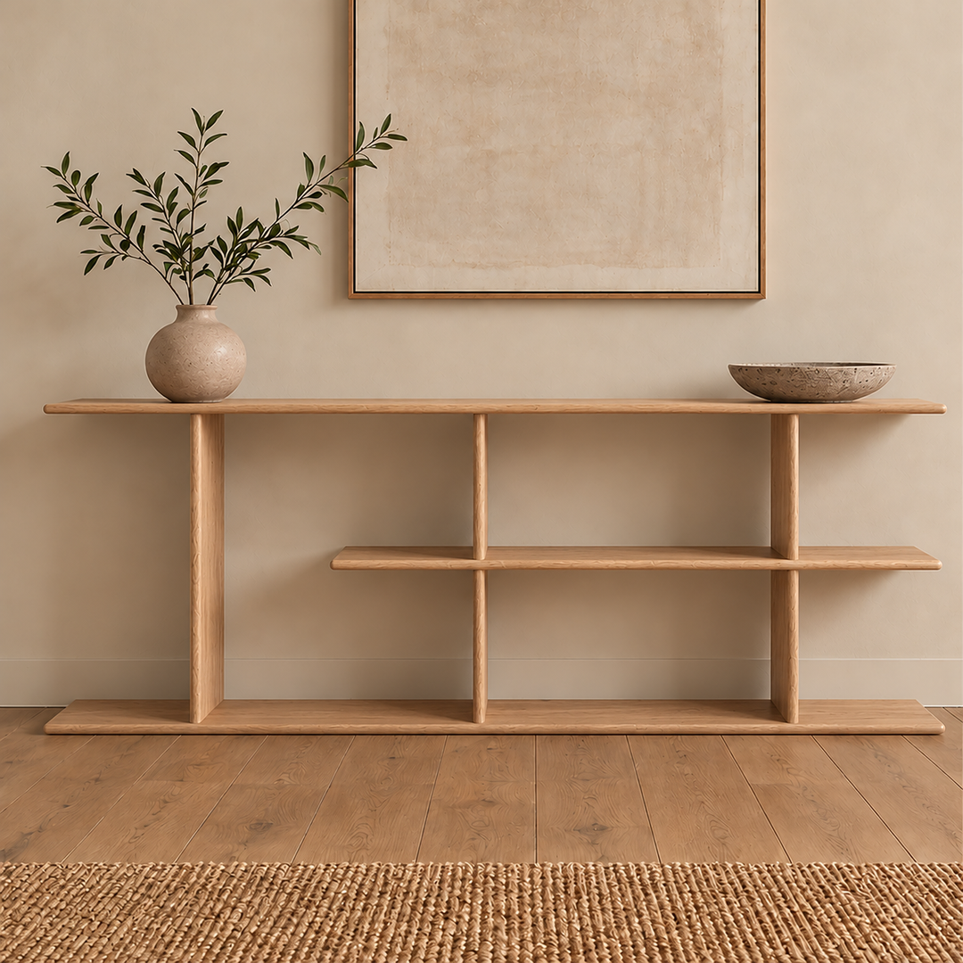 The staggered shelf bookcase in white oak styled with a vase of olive branches and a stone bowl, below a framed print.