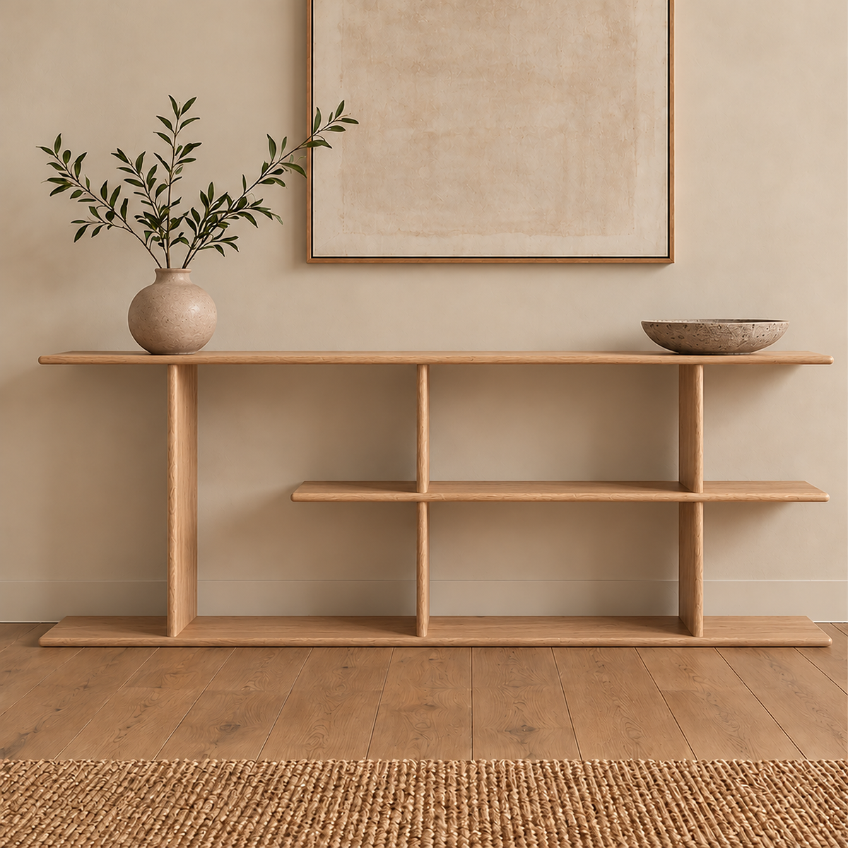 The staggered shelf bookcase in white oak styled with a vase of olive branches and a stone bowl, below a framed print.