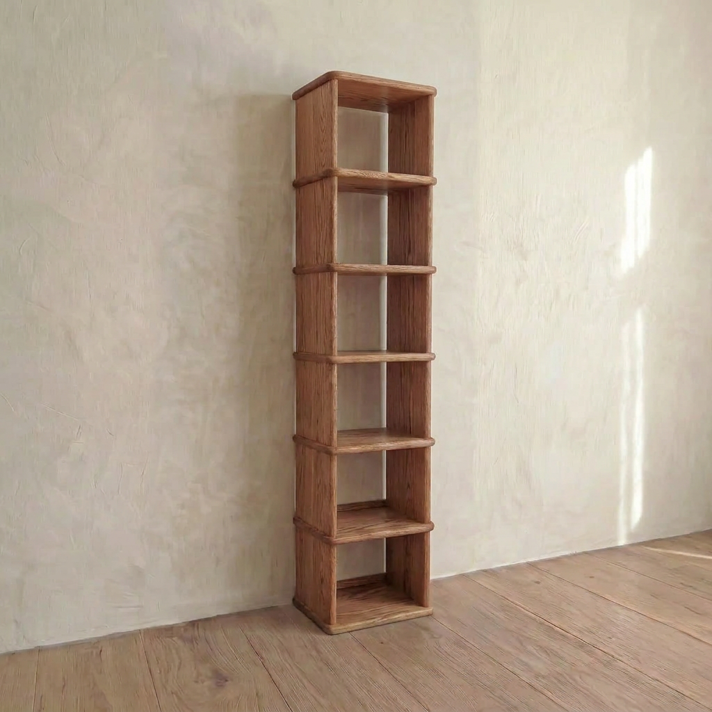 A Tall narrow bookcase in red oak with six shelves stands against a light-colored textured wall on a wooden floor in a minimally decorated room.