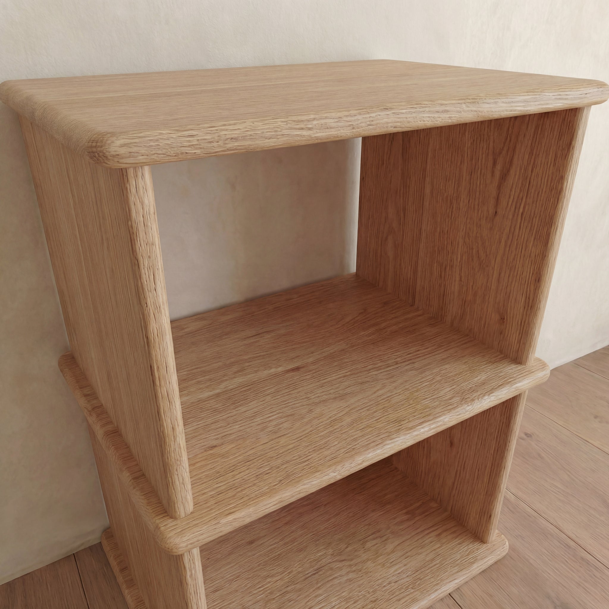 A close-up view of the Nightstand bookshelf in white oak, featuring two open shelves, placed against a beige wall on a wooden floor.