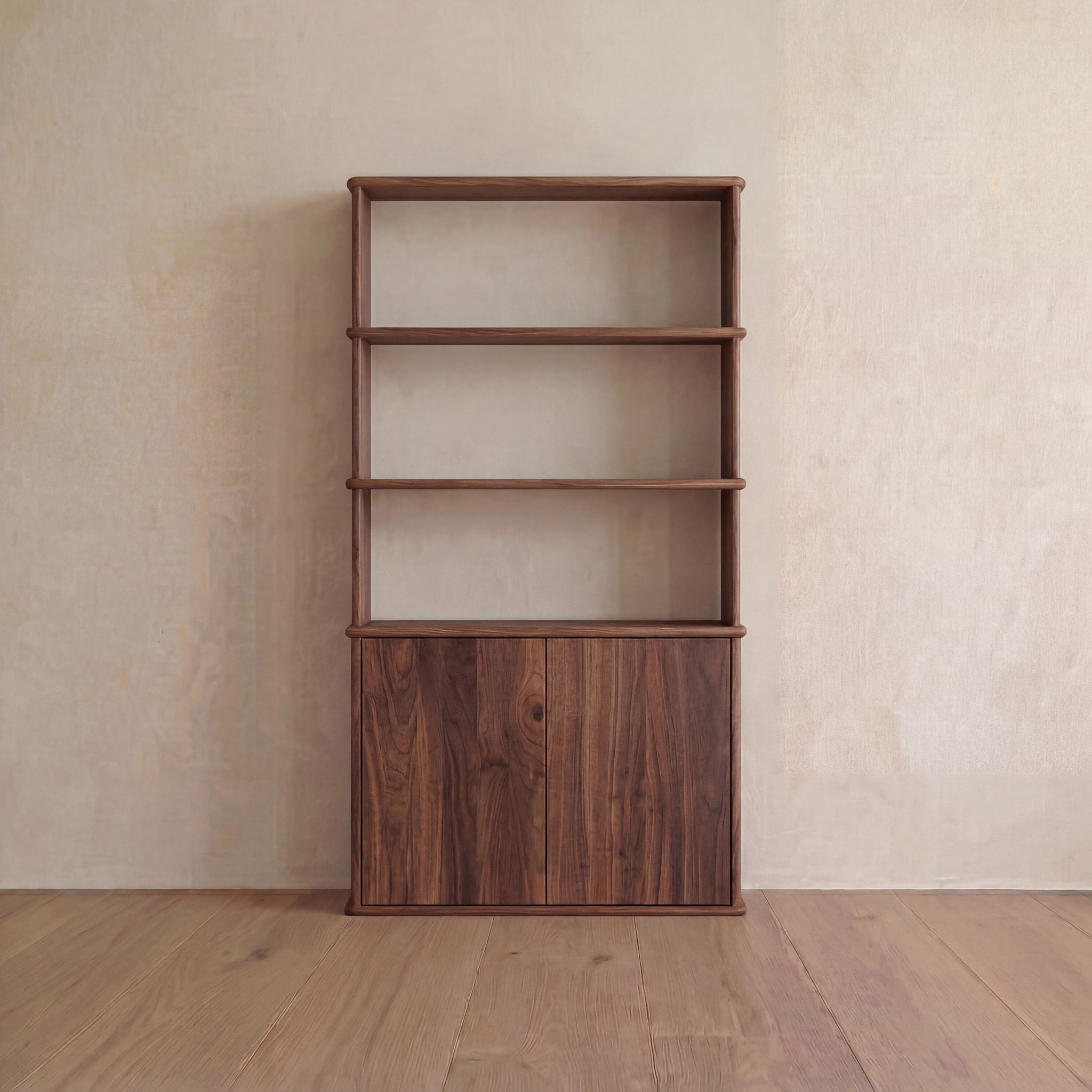 A Cabinet bookshelf in walnut featuring three open shelves on top and a two-door push-to-open cabinet at the bottom, positioned against a light-colored wall on a wooden floor.