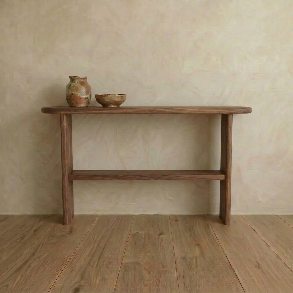 A Console table with shelf in walnut, handmade in Vancouver, stands against a beige textured wall. Two rustic ceramic vessels on top enhance the calm, natural aesthetic alongside the room’s wooden floor.